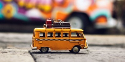 a toy bus with suitcases on it in front of a graffiti wall