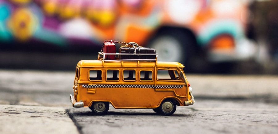 a toy bus with suitcases on it in front of a graffiti wall