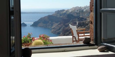 looking out a window onto a balcony overlooking mountains and ocean