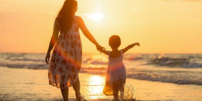 Young Mother On The Beach With Daughter At Sunset