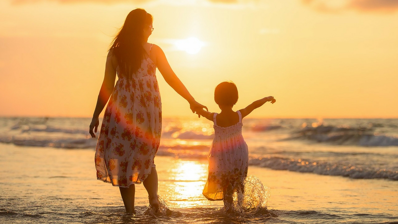 Young Mother On The Beach With Daughter At Sunset