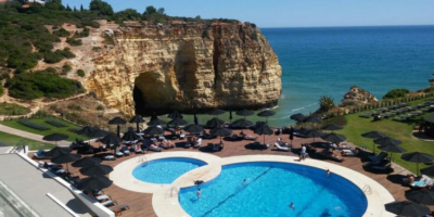 image of hotel swimming pool in portugal from high vantage point. rocks and the sea are in the background