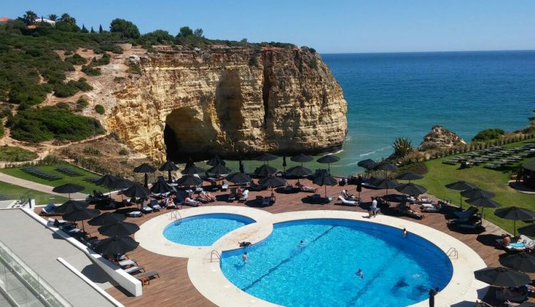 image of hotel swimming pool in portugal from high vantage point. rocks and the sea are in the background
