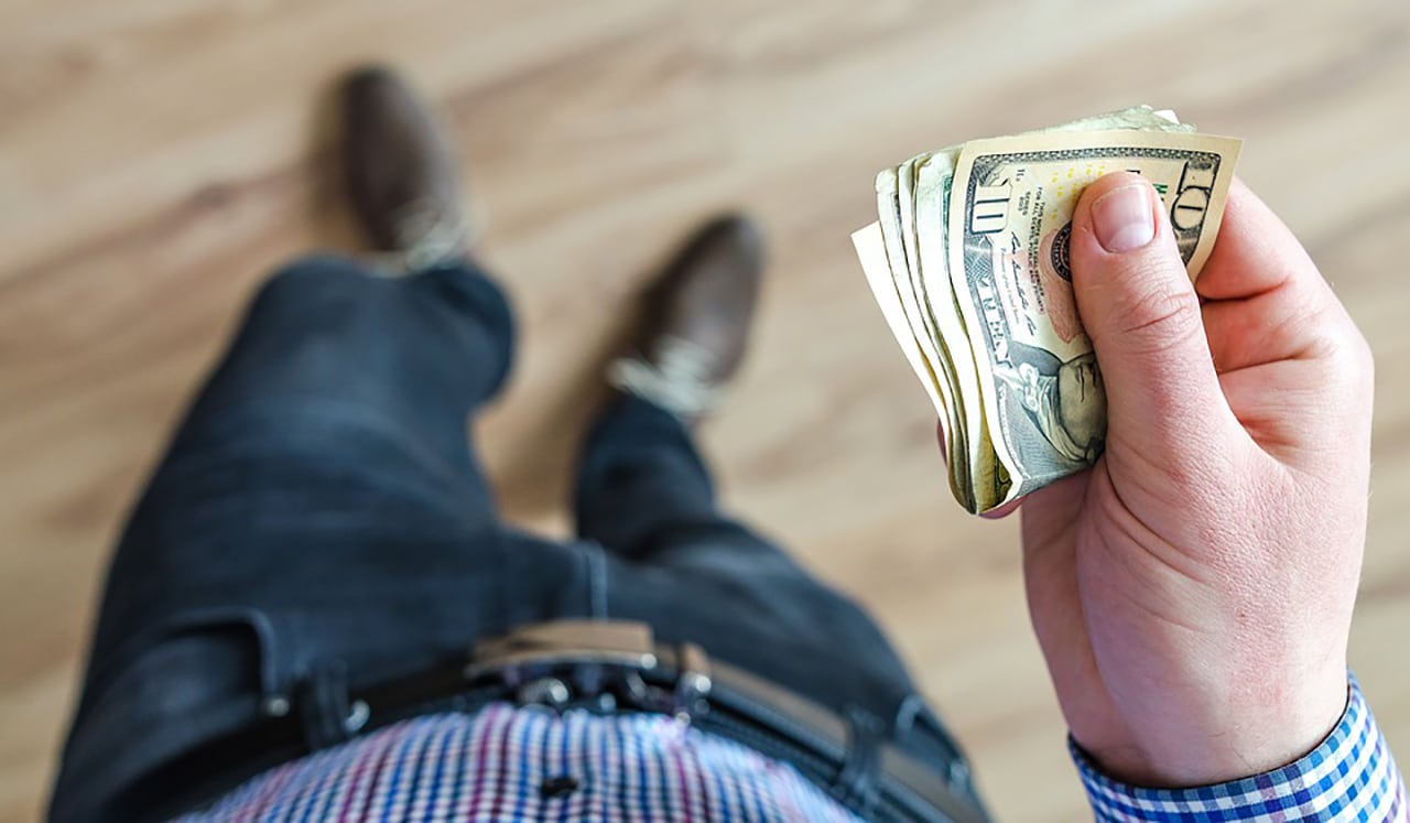 Man holding wad of U.S. dollars in cash