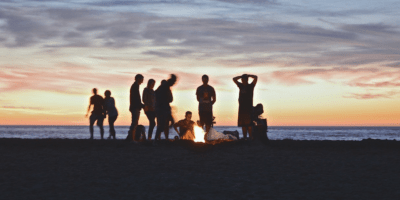 Friends enjoy a fire at the beach at sunst