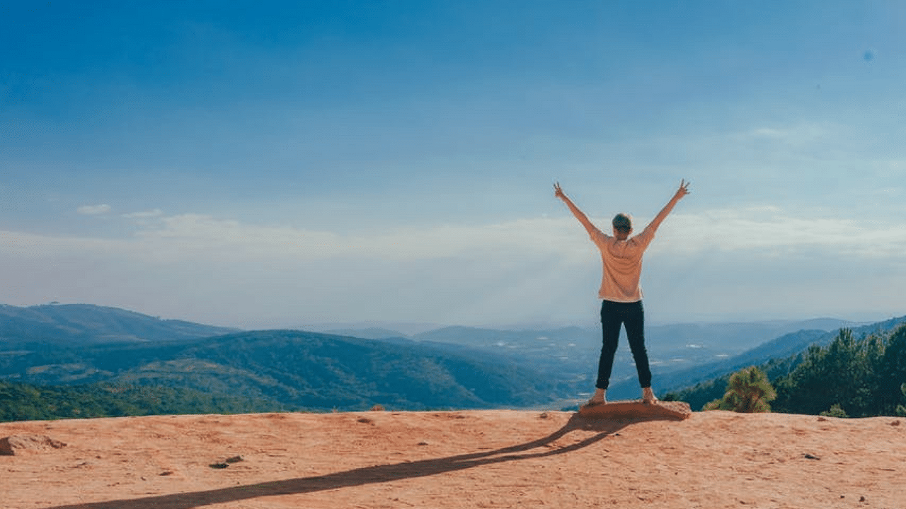 Person holding his arms in the air looking out over the mountains