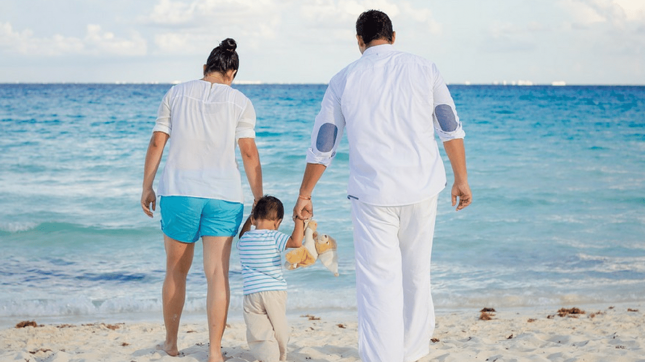 Prents hold thier child's hand at the beach