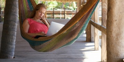 A woman works at her laptop in a hammock