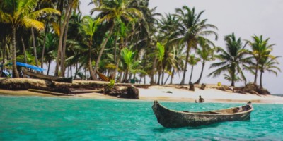 a traditional canoe in San Blas with blue water and palm trees