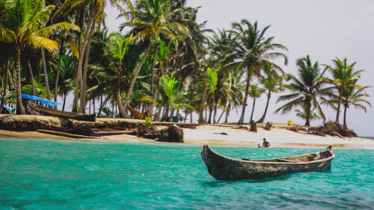 a traditional canoe in San Blas with blue water and palm trees