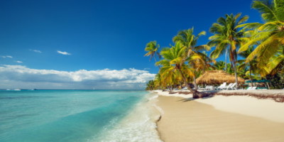 An idylic beach on the Dominican Republic with palm trees and clear blue seas