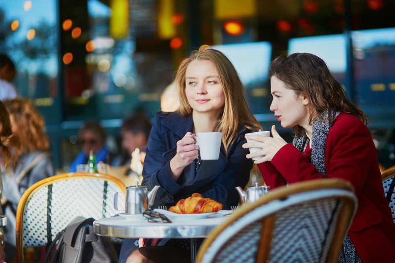 friends in paris cafe having coffe and talking