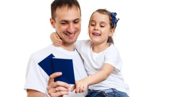 Dad with hands up holding two passports and daughter. Second residency concept.