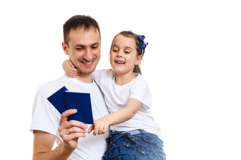 Dad with hands up holding two passports and daughter. Second residency concept.