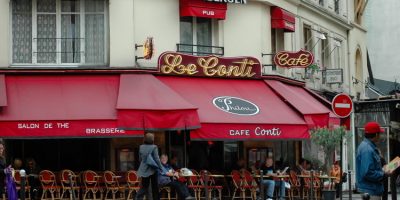 Locals and tourists sitting and the brasserie cafe restaurant in Paris reading morning newspapers and enjoying coffee.