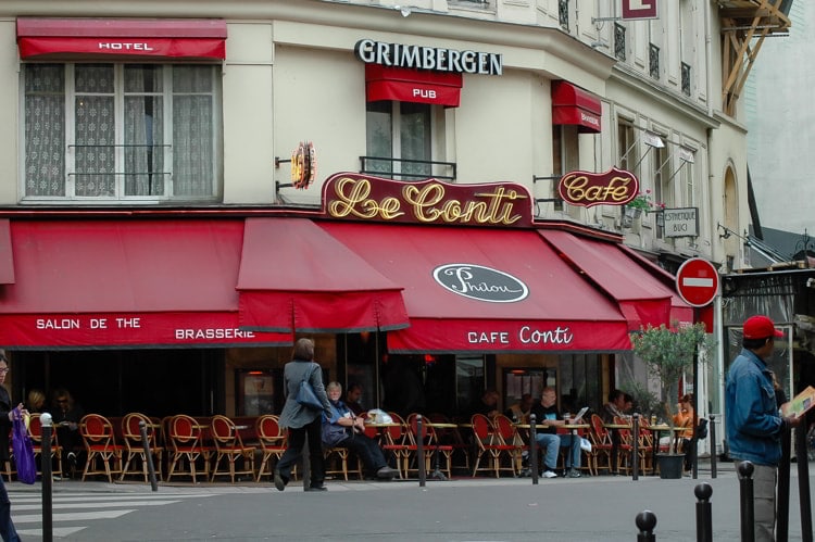 Locals and tourists sitting and the brasserie cafe restaurant in Paris reading morning newspapers and enjoying coffee.
