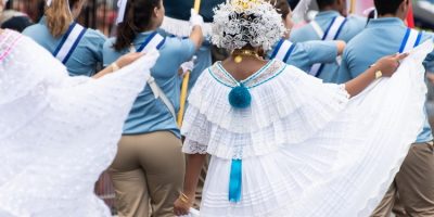 Woman wearing traditional white Panamanian dress and other people in the street during Panama National Day parade