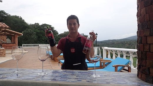 A man with two bottles of wines and two wine glasses getting ready for wine testing