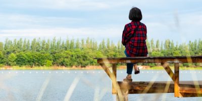 Senior retired woman sitting on the pier enjoying the view of lake