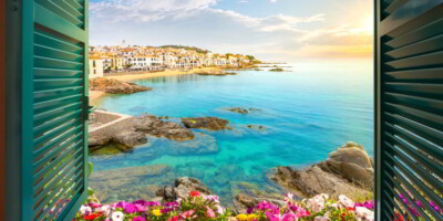 View through an open window with shutters of the whitewashed Costa Brava village of Calella de Palafrugell, Spain