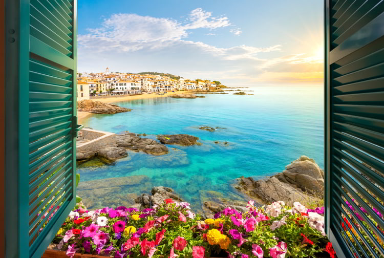 View through an open window with shutters of the whitewashed Costa Brava village of Calella de Palafrugell, Spain